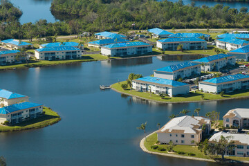 Hurricane damaged apartment buildings rooftops covered with protective plastic tarp against rain water leaking until replacement of asphalt shingles. Aftermath of natural disaster
