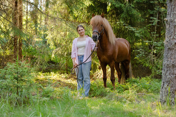 Woman with Icenlandic horse in forest with sunset on behind