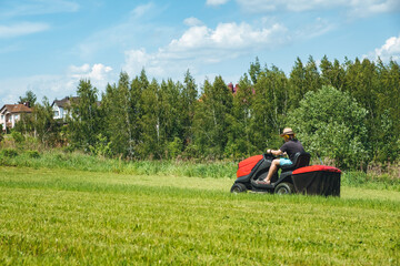 Obraz premium Man on lawn tractor mowing lawn on backyard. The red rider. The lawnmower tractor. High quality 4k footage
