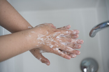 Fototapeta premium Hygiene and cleaning hands.Washing hands rubbing with soap for corona virus prevention, hygiene to stop spreading coronavirus.Close up woman hand washing in the kitchen.