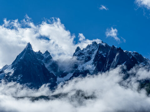 les aiguilles &agrave; chamonix, dans les nuages avec ciel bleu et soleil qui jouent &agrave; cache cache