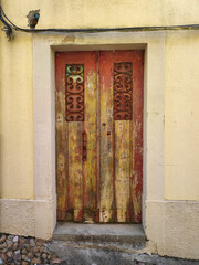 Old rustic wooden door with wrought iron details on a yellow wall