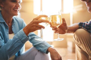 Mature couple, toast and champagne in new house with boxes, smile and celebration for deal at property. People, woman and man with relocation, cheers and drinks on floor with real estate in Spain