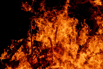 Obraz premium A dramatic image of a fierce fire burning intensely against the dark night sky. The bright orange and yellow flames highlight the raw energy and destructive power of the blaze. Copy space available.