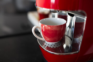 Close-up view of red espresso machine and small cup.