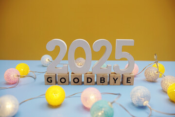 Goodbye 2025 letters with LED cotton balls decoration on blue background