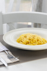 Portion of penne pasta with yellow on a white plate. Dinner