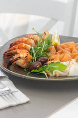 Fish platter salmon and oily fish. On a large plate. Garnished with a slice of lemon and herbs.