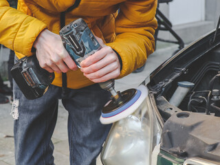 Hands of a man polishing a car headlight