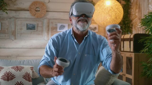 Happy grandfather having fun playing games using VR headset at home, old man playing game using virtual reality glasses