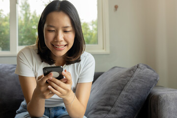 close up young asian woman use smartphone for check notification or read news or alert from application in living room at home for people lifestyle and technology concept