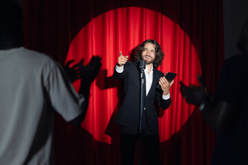Stand up comedian on stage. Young man talks joke into microphone or sings songs