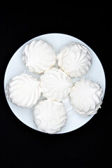 Marshmallows on a white plate. Sweet white marshmallows in round slices.