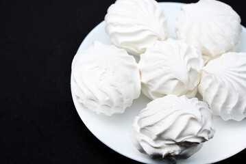 Marshmallows on a white plate. Sweet white marshmallows in round slices.