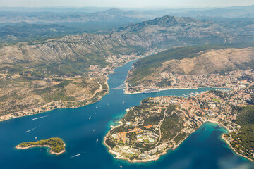 Aerial aviation airplane image of the historic ancient city of Dubrovnik in Croatia along the Adriatic Sea coast line. Many medieval brick houses surrounded by defence wall, battlement, rugged nature