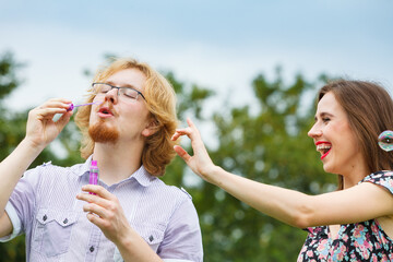 Couple blowing soap bubbles, having fun