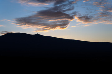 A VIEW OF MOUNT VENTOUX WITH A DARK FOREGROUND AND A CLEAR SKY WITH ONE MOODY CLOUD IN THE PROVENCE REGION OF FRANCE