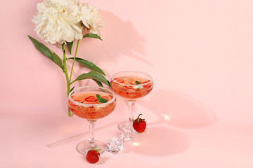 Modern still life with pink martini, alcoholic cocktail, strawberries and peony flowers on elegant modern background, minimal concept for bar and holiday party, cafe, advertising banner, 