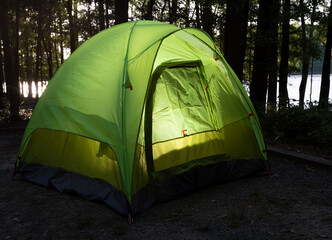 Sun rising over a dark forest with a tent