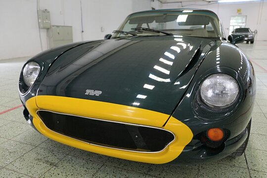 Left front view of two-seater british sports car TVR Chimaera, dark green color with yellow mouth like line around the front mask, displayed on tuning and car expo in Nitra, Slovakia, june 2024.