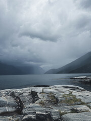 Gloomy Nordic fjords and rocks. Vertical photo with mystic landscape in Norway.