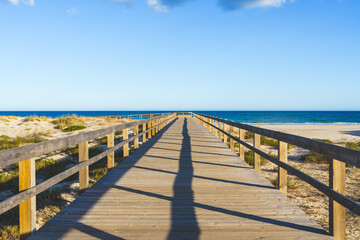 Sand dunes at sunset and a long wooden boardwalk leading to the beach