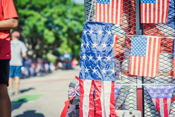 Windsocks American flag and dense string of flags on July Fourth parade, blurry diverse participants, Red White Blue Streamers fringe curtain on steel mesh utility trailer truck, Independence Day