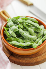 Green edamame pods. Fresh soybeans in bowl on cutting board.
