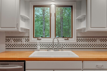 Modern Kitchen With White Cabinetry, Wooden Countertop And Large Window View