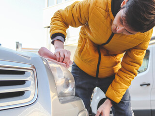 Young man polishing a headlight with a rag