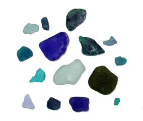 Collection of smooth, colorful sea glass pieces are scattered on transparent background. Sea glass is of various sizes and shapes, and includes colors such as blue, green, purple and white.