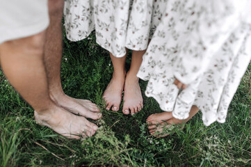 Barefoot man, woman and child girl, happy healthy family standing on the grass in a field. Close up photo of feet close up of dad, mom, daughter, lifestyle, love concept.