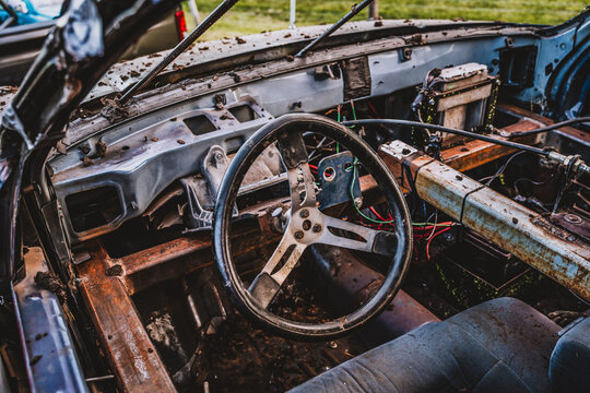 Steering wheel, structural support, and stripped interior of a demolition derby car. 