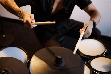 Partial shot of tattooed musician playing drums in studio