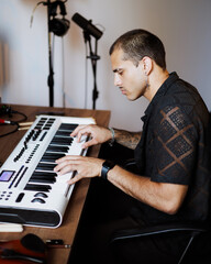 Young mixed race pianist playing synthesizer in music studio