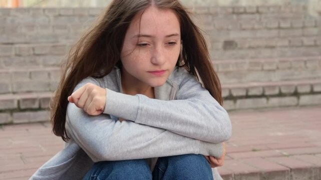 Sad depressed teenage girl alone on the street, feeling angry and lonely. Growing crisis and anxiety. Concept of self-acceptance and self-analysis.