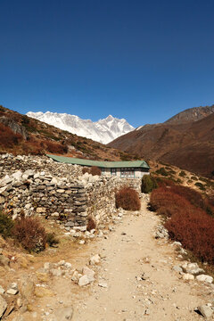 A teahouse surrounded by a stone wall outside of the village of Shomare, Mount Nuptse and Lhotse can be seen in the background, Mount Everst Base Camp Trek, EBC, Nepal