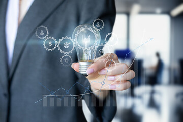 Businesswoman shows a burning light bulb .