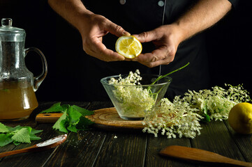 A chef adds lemon to elderflowers before making kvass on the kitchen counter.
