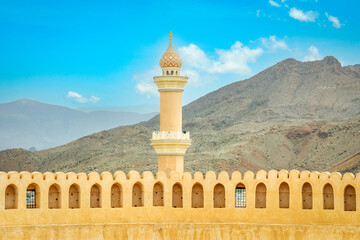 Al Qala'a Mosque ornated dome and minaret with Nizwa castle walls in the foreground, Nizwa,...