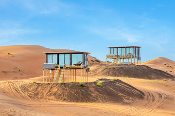 Desert hotel houses standing above the sands in the middle of Wahiba desert, Oman