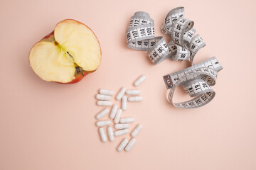 Measuring tape and tablets, vitamins on a colored background with space for text. Concept of losing weight, dieting, burning fat, healthy eating