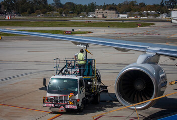 A fuel handler on an aviation refueler truck pumping jet fuel into the wing of a commercial airplane