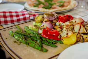 grilled vegetables on the grill. potatoes, mushrooms, green asparagus on a wooden board on the table.