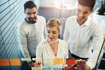 Business people, brainstorming and planning with glass board, project strategy or sticky note in office. Lens flare, diversity and employees in meeting for writing ideas, agenda or collaboration