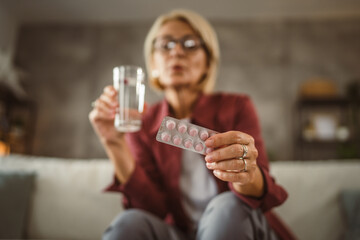 Mature senior woman drink medicine with glass of water at home