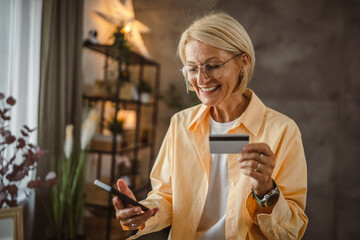 Fototapeta premium Mature senior woman buy online on mobile and use credit card