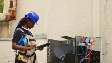 Qualified electrician servicing outdoor condenser internal components, checking freon level and...