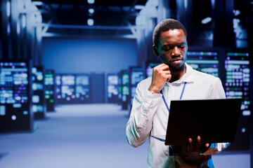 Electrician inspecting blade servers delivering online web content to customers. African american...
