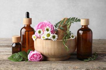 Aromatherapy. Different essential oils, flowers, mortar and pestle on wooden table